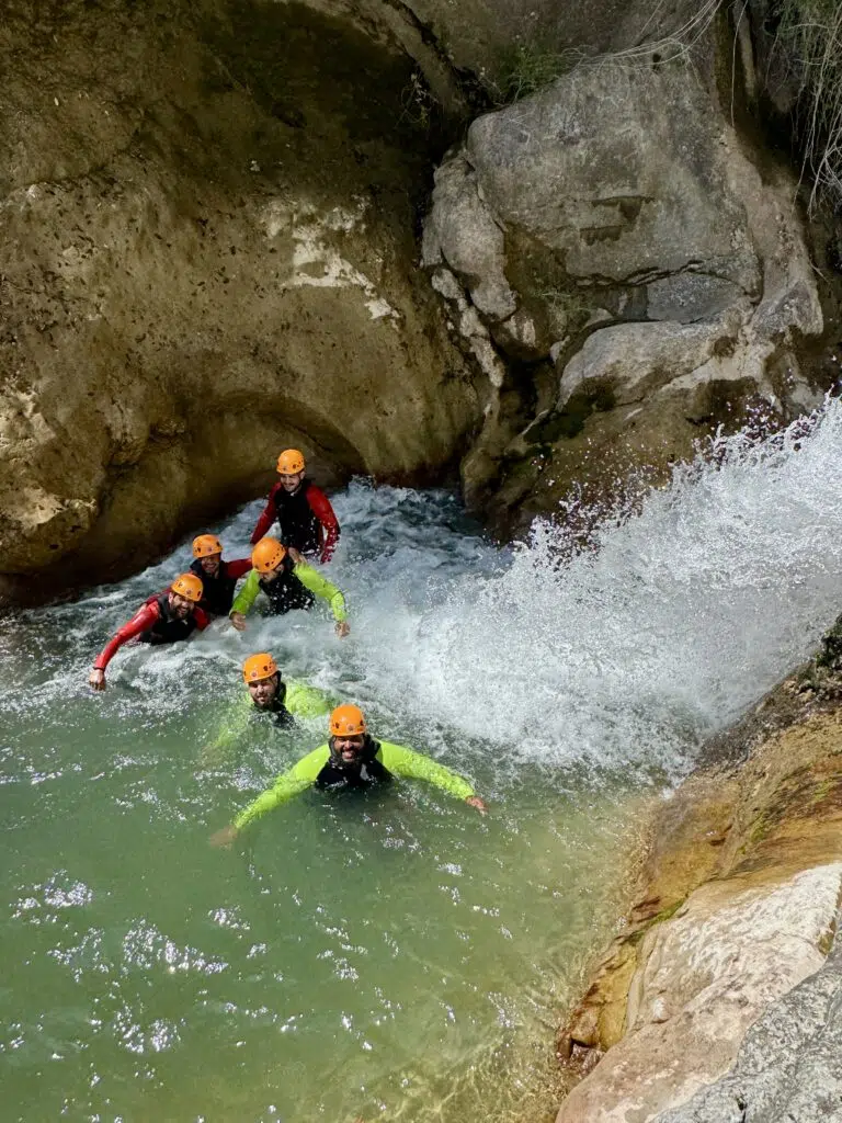 A group swimming in a turquoise pool at the foot of a waterfall, canyoning in Bandol with Ailéments